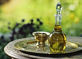 Body oil in glass bottle with stopper and brass dish on tray
