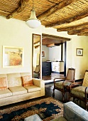 Elegante Antikmöbel im Wohnzimmer eines Landhauses mit traditioneller Holzbalkendecke