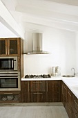 Eine interessante Mischung aus rustikalen Holzfronten und modernen Einbaugeräten in der Küche mit Dachschräge