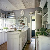 Ein Kronleuchter, ein eleganter Spiegel und dekorative Zierleisten an den Küchenmöbeln machen die verspielte Romantik der Küche aus