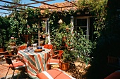 Gedeckter, bunter Gartentisch auf einer schönen, reich begrünten Terrasse
