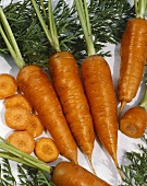 Whole and sliced carrots on white background