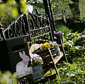 Garden seat in front of garden gate with pansies in containers