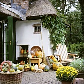 Pumpkins and autumn flowers outside thatched house