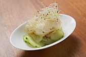 A tempura appetiser on spicy cucumber salad with sprouts