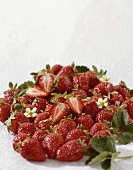 Whole and halved strawberries with leaves and flowers