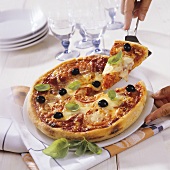 Ein Stück Pizza Margherita mit einem Tortenheber nehmen
