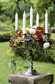 Candlestick decorated with flowers on pedestal out of doors