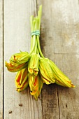 A bunch of courgette flowers on a wooden surface