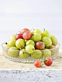 Red and green gooseberries in a glass bowl