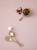 Dried flowers in a tea strainer and a sugar cube on a spoon
