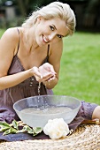 A blonde woman scooping water out of a bowl
