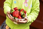 A girl holding a bowl of strawberries