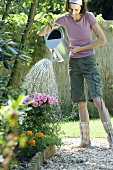 A young woman watering flowers in a garden