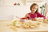 A girl brushing shortbread biscuits with jam