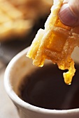 A waffle being dunked in syrup