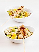 Chicken kebabs on a rice salad with pineapple and avocado