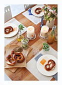 A table laid with pretzels, cheese in oil and ginger drinks