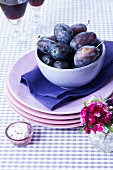 A bowl of damsons on a stack of plates