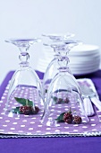 Washed glasses with blackberries underneath them on napkins