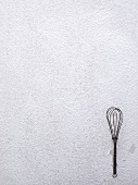 A whisk on icing sugar