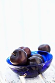 Plums in glass bowl on wooden chair