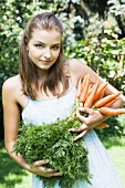 Woman holding fresh carrots in garden