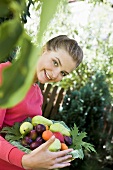 Woman holding bowl of fruit in garden