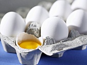 Ganzes und aufgeschlagenes Ei im Eierkarton