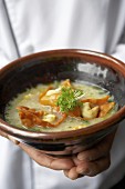 Chef holding a bowl of shrimp congee with wontons
