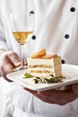 Chef carrying a piece of cream cake on a plate & dessert wine