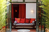 Blick durch geöffnete Terrassentür auf Holzsofa mit Sitzkissen