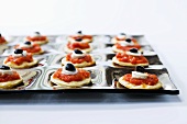 Canapes topped with tomato sauce, mozzarella and olives
