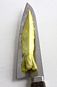 A piece of Japanese horseradish on a knife blade