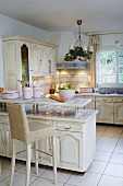 Blick in weiße Landhausküche mit Küchentheke & Stuhl