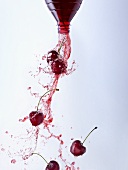 Cherry juice and cherries pouring out of a bottle