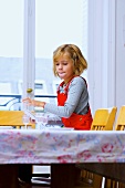 Kleines Mädchen deckt den Esstisch