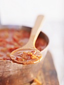 Tomato sauce on wooden spoon and in pan