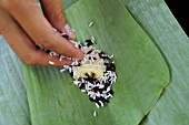 Stuffing a banana leaf with rice and banana