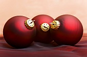 Three dark red Christmas baubles