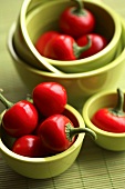 Several cherry peppers in green bowls
