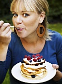 Woman eating pancakes with cream and berries