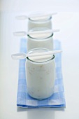 Three jars of yoghurt with plastic spoons
