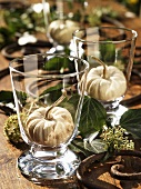 Ornamental gourds in glasses (autumn table decoration)