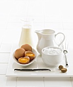 Baking ingredients (eggs, sugar, vanilla pod, nutmeg, milk) & whisk