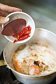 Putting chillies into pan (Thailand)