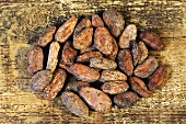 Viele Kakaobohnen auf Holzuntergrund (Draufsicht)