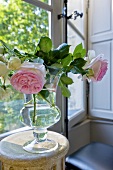 Roses in glass vase on occasional table by window
