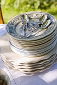 Stack of plates with spoons on table in garden