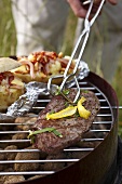 Beefsteak and baked potatoes on a barbecue